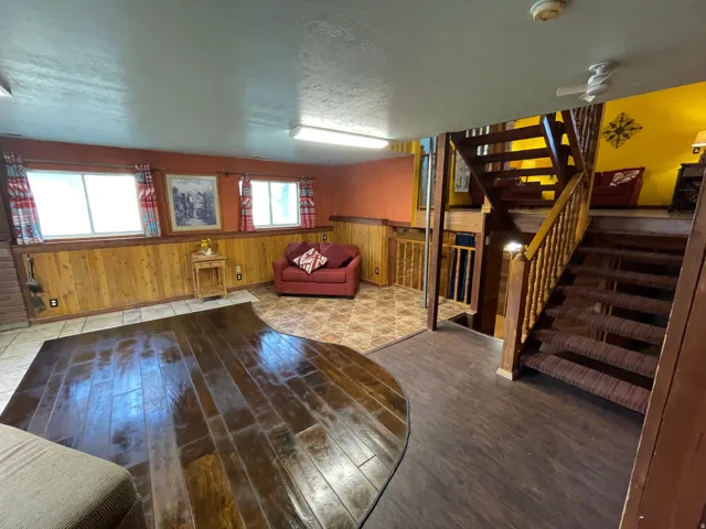 Lower level living space featuring a wood-finish flooring area, a tiled section, and wood paneling