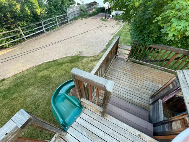 Multi-level wood deck featuring a built-in green slide and wood railings