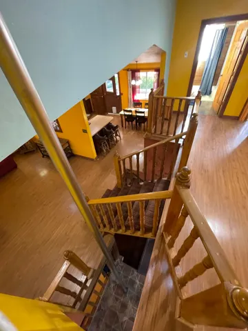 Multi-level interior featuring wood-finish flooring, a wood staircase with balusters, and a tiled landing