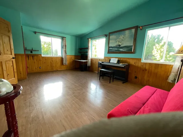 Spacious room featuring wood-finish flooring, half-wall wood paneling, and an angled ceiling