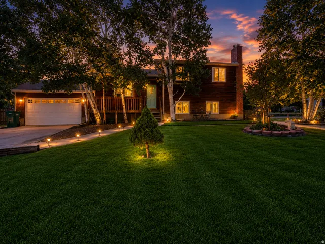 Expansive front lawn with manicured grass and mature trees