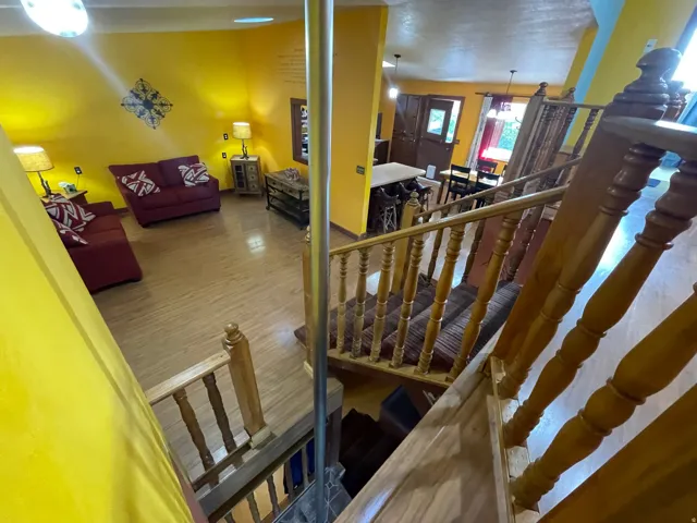Multi-level interior featuring wood stairs with turned balusters, wood-finish flooring, and bright yellow wall finishes