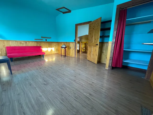 Interior space featuring wood-finish flooring, half-wall wainscoting, and a built-in shelving unit