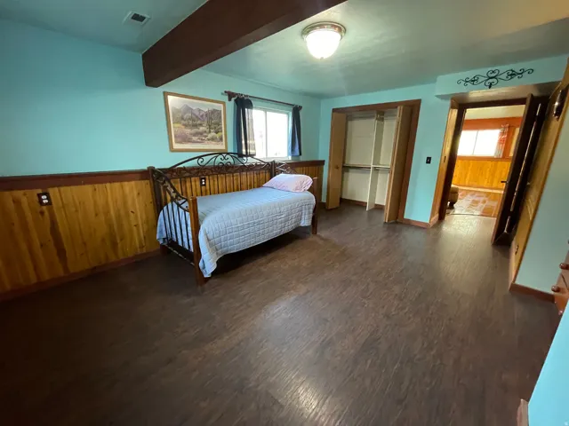 Spacious room featuring wood-finish flooring, wood paneling, and a built-in closet with shelving