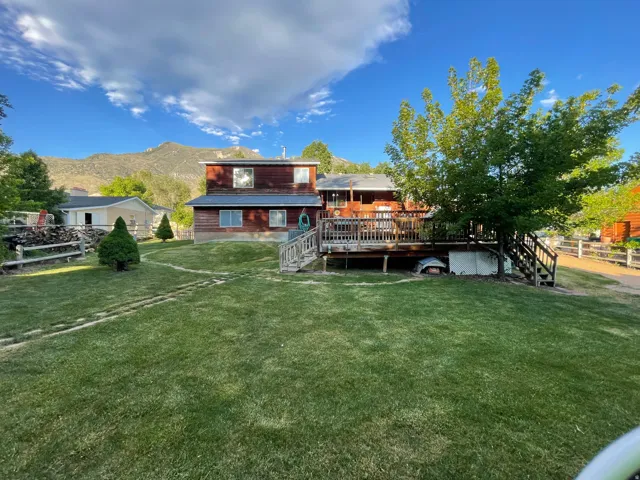 Expansive green lawn with mature trees and a multi-level wood deck