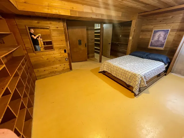 Wood-paneled room featuring built-in shelving, a recessed mirror, and a solid core door