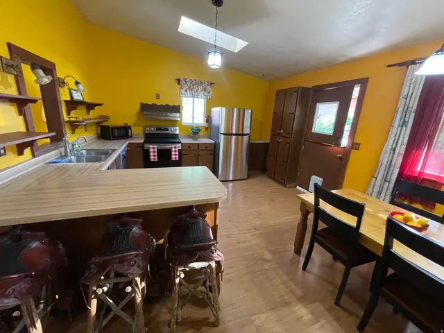 Kitchen featuring a skylight, wood-finish flooring, a double basin sink, and stainless steel appliances