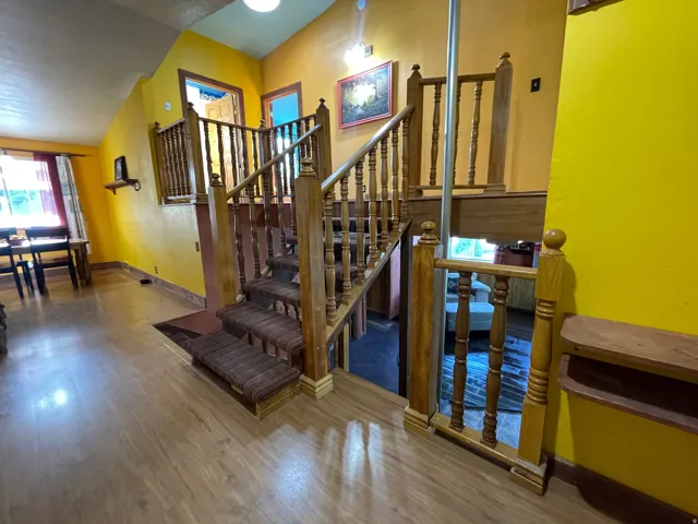 Wood-finish flooring throughout, complemented by a wooden staircase featuring carpeted treads and carved balusters