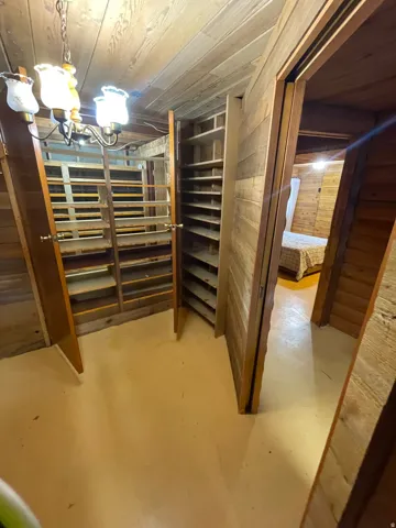 Wood-paneled room featuring extensive built-in shelving, a ceiling-mounted light fixture, and a light-toned floor