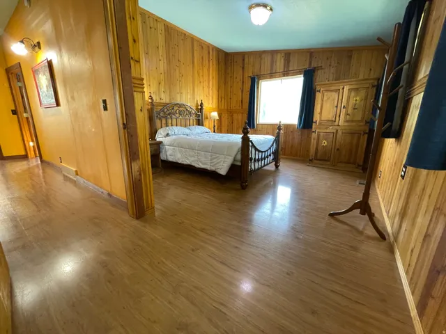 Room featuring wood-finish flooring, wood-paneled walls, and a window with dark curtains