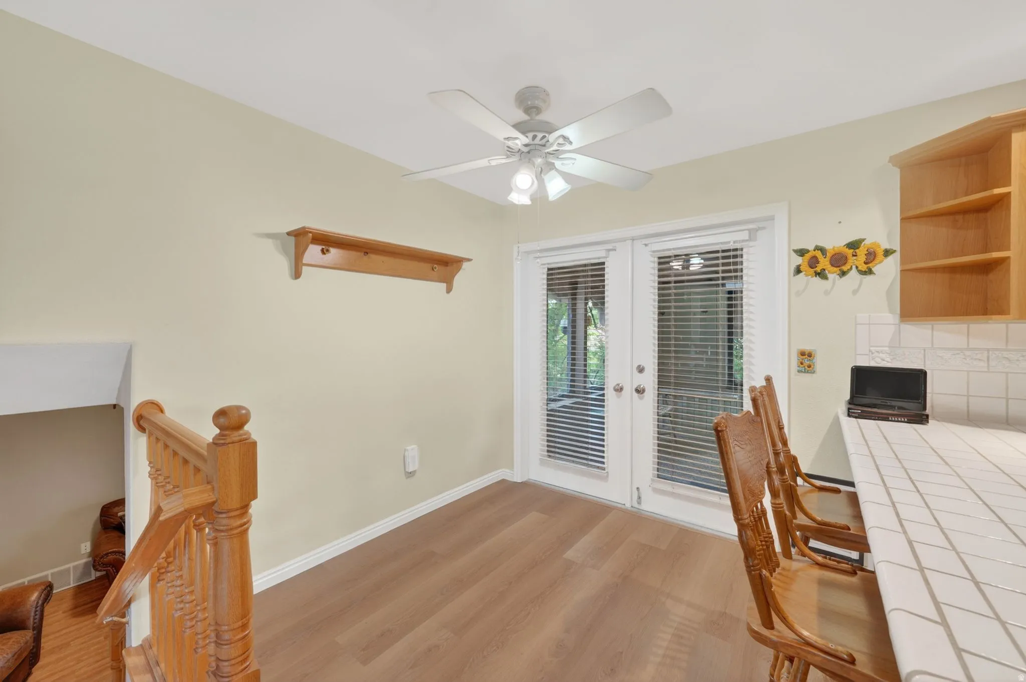 Room featuring wood-finish flooring, a ceiling fan, and white French doors