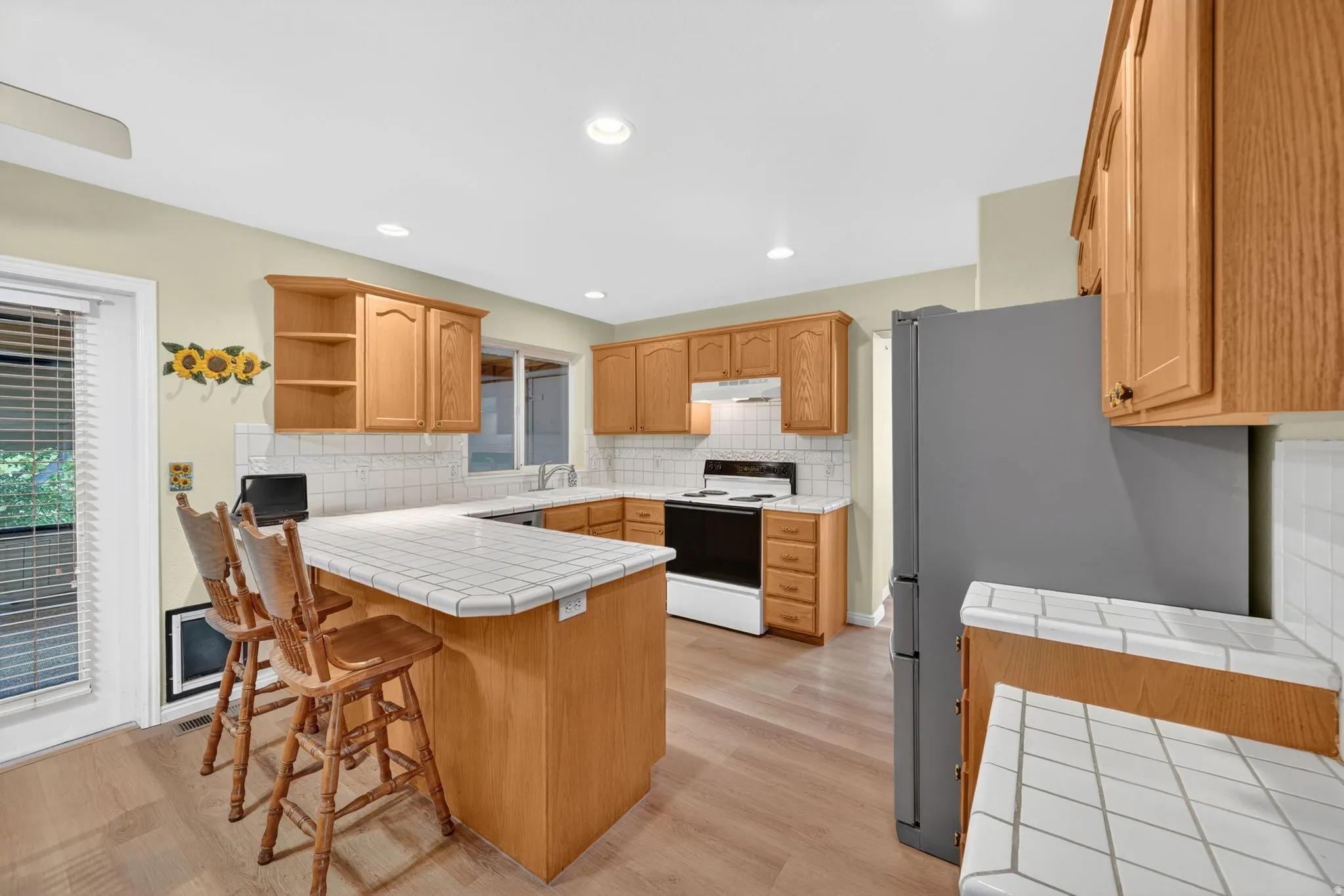 Kitchen featuring wood-finish flooring, light wood cabinetry, and a tile countertop