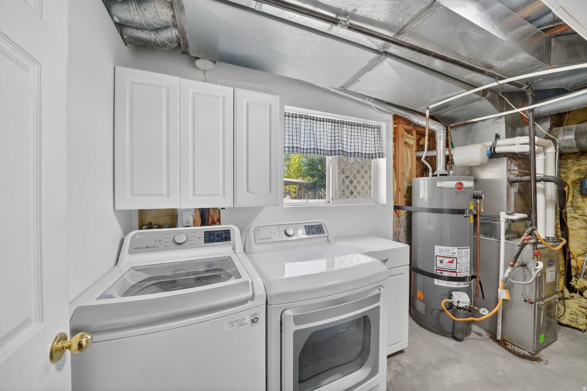 Laundry area featuring concrete flooring, overhead cabinetry, and a window for natural light