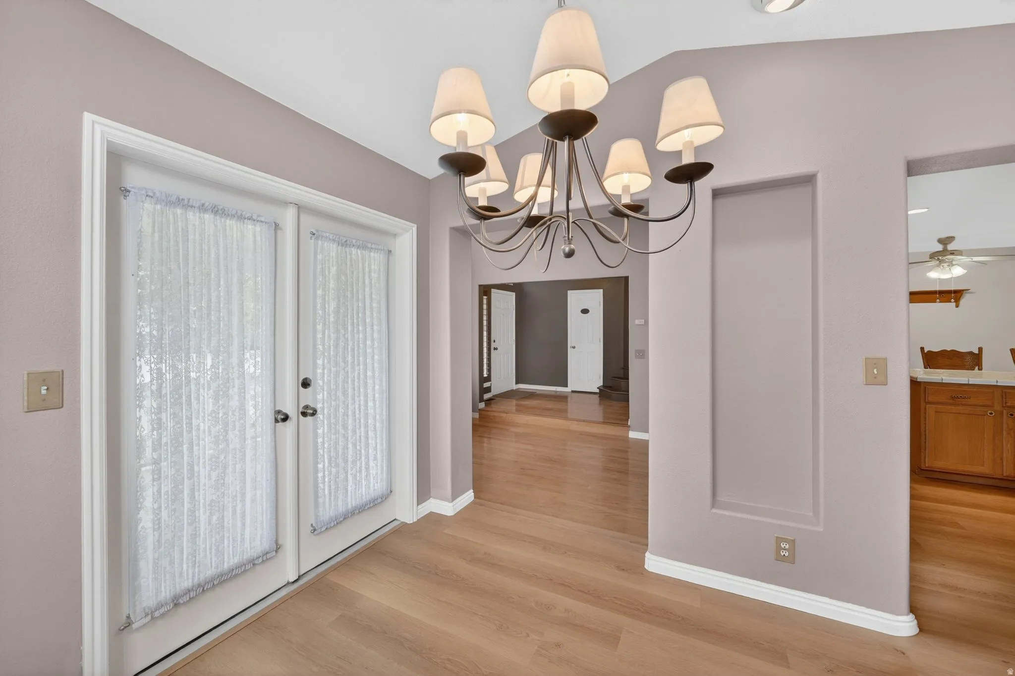 Wood-finish flooring throughout, featuring a multi-light chandelier, recessed lighting, and white baseboards