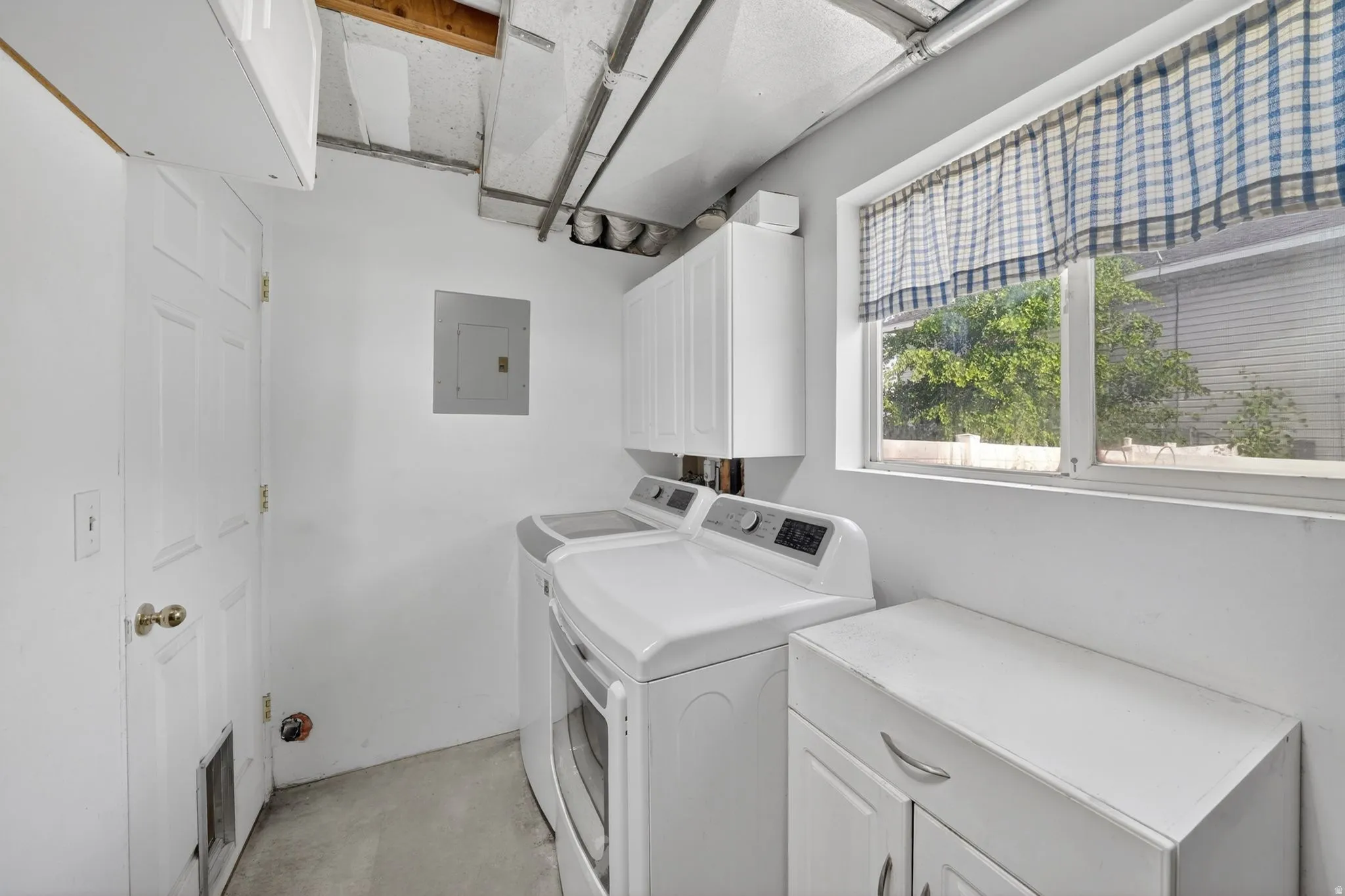 Dedicated utility area featuring white cabinetry, a white paneled door, and a single window