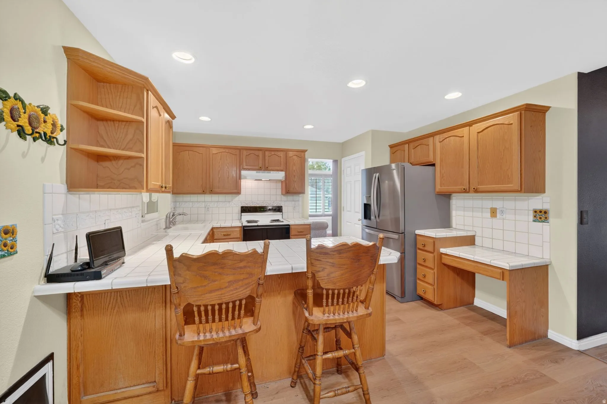Kitchen with wood cabinetry, white tile countertops, and a full suite of stainless steel appliances