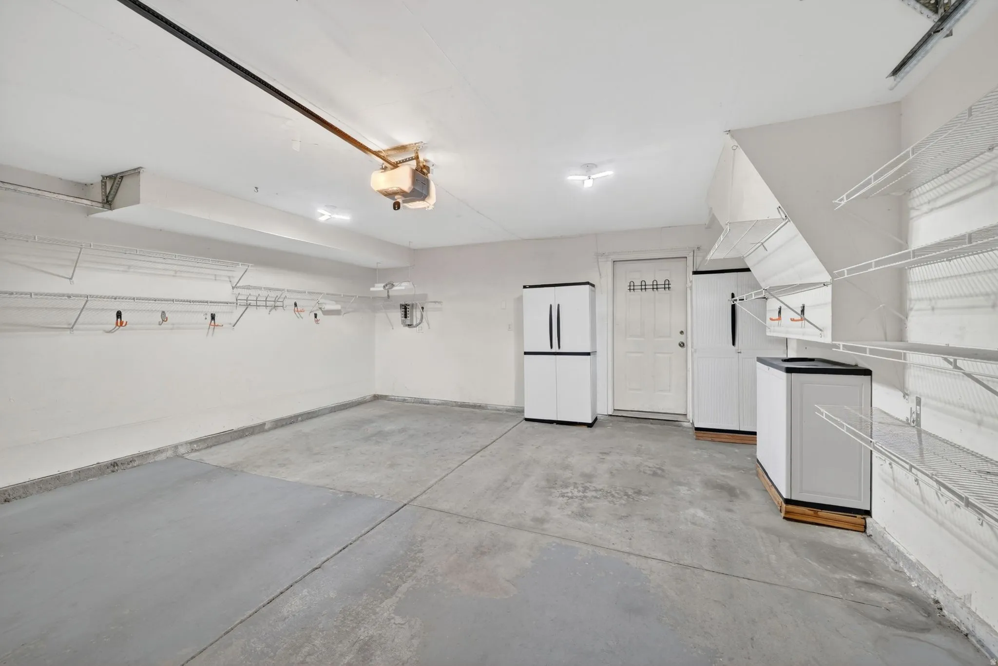 Spacious garage with light grey concrete flooring and white painted walls