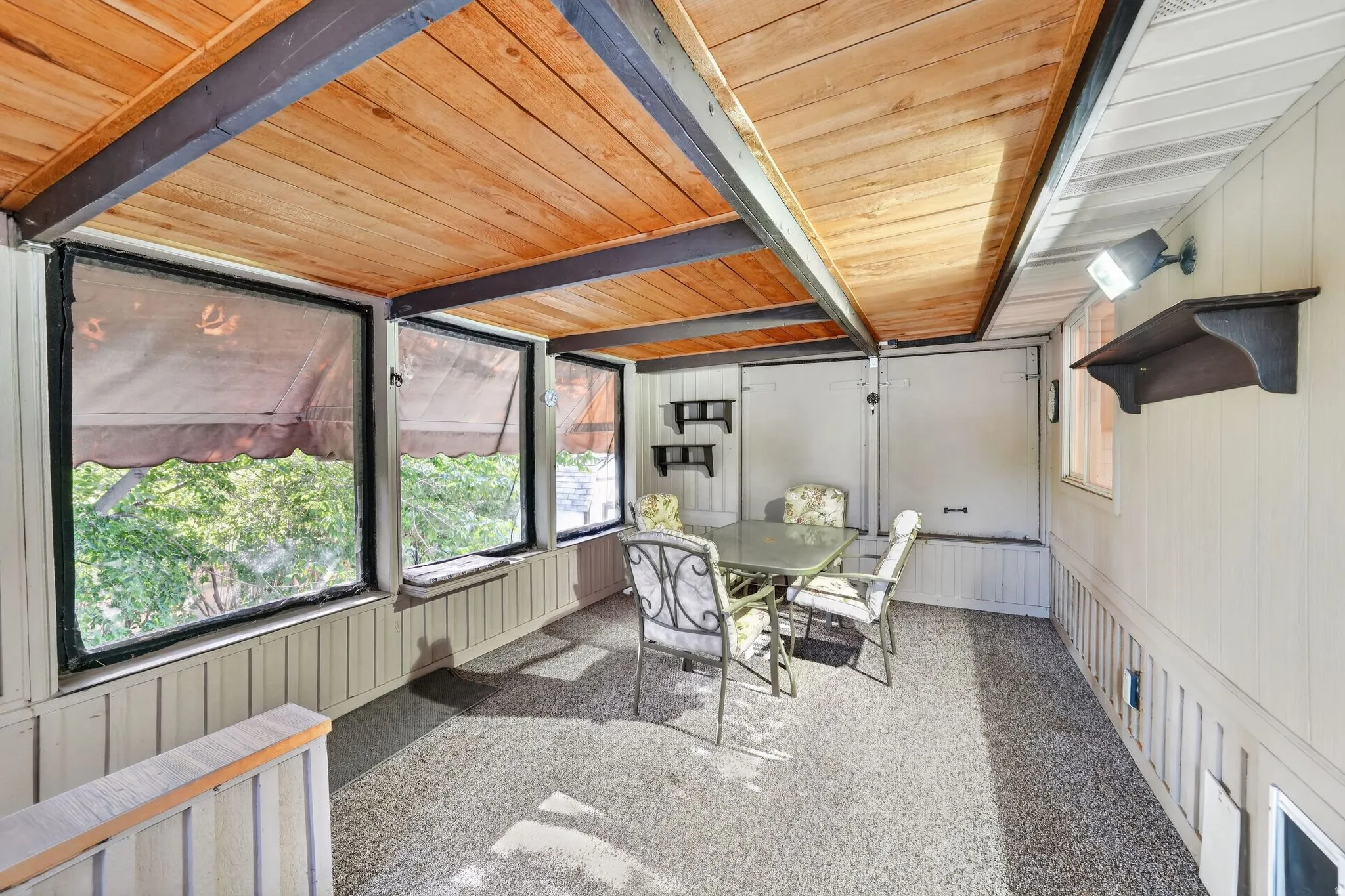 Enclosed porch with a wood-plank ceiling, exposed beams, and a textured floor