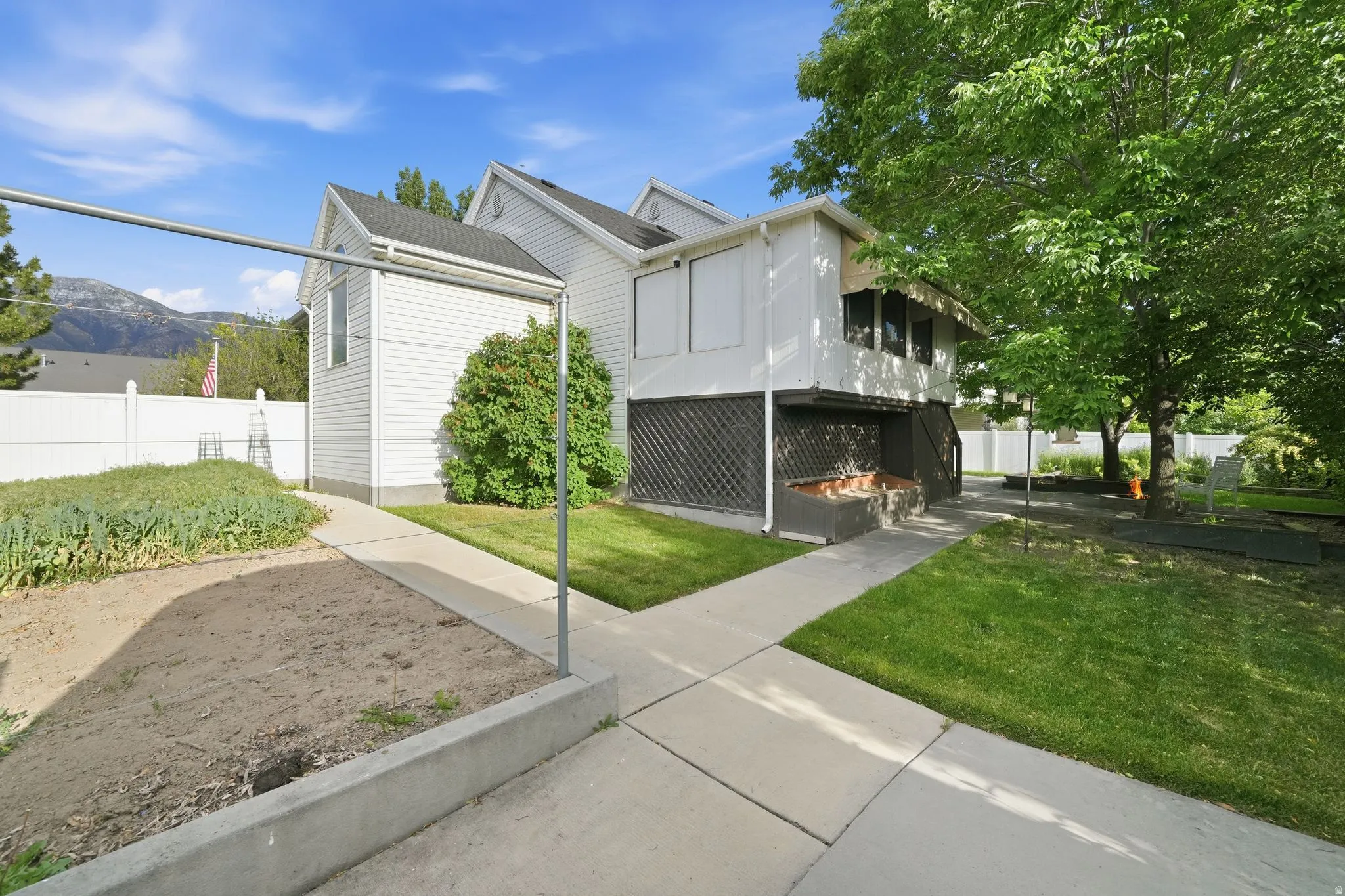 Expansive rear yard featuring a manicured lawn, concrete pathways, and a raised garden bed