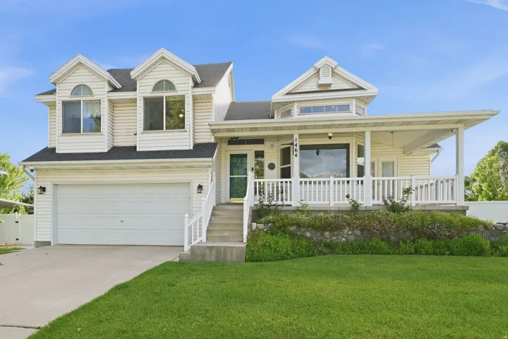 Two-story residence featuring light-colored siding, a covered front porch with white railings, and a two-car garage