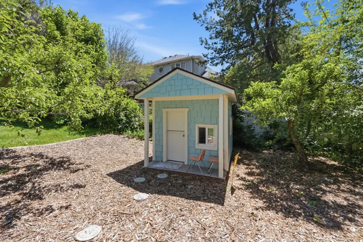 Light blue shingle-sided shed with a white trim and a small porch