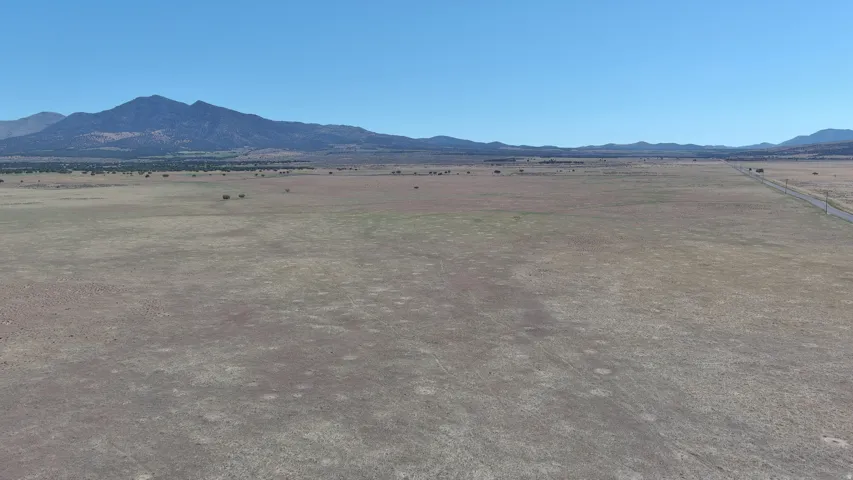 Expansive undeveloped land featuring a distant mountain range, a clear horizon, and a visible road