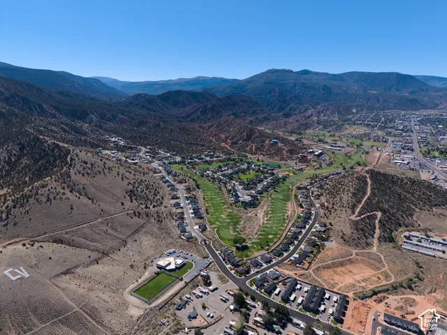 Aerial overview of a residential community with a golf course, surrounded by mountainous terrain