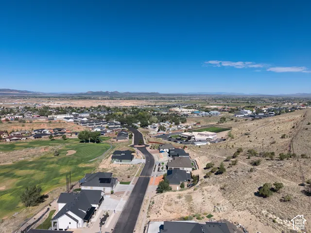 Looking West:  Newly developed residential area with paved streets and contemporary homes, bordering a golf course and natural desert landscape, all set against a backdrop of distant mountains