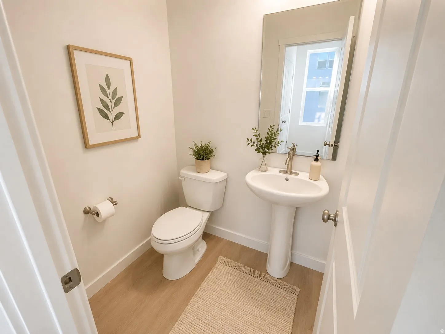 Powder room featuring a pedestal sink, white toilet, and wood-finish flooring