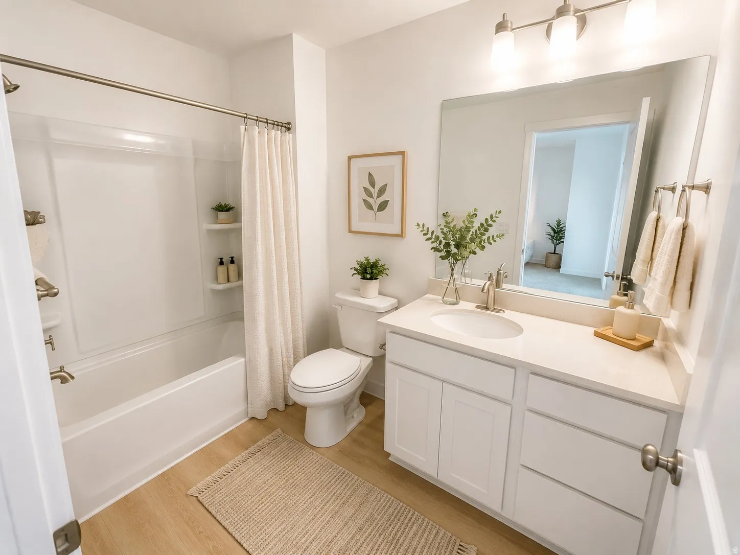 Full bathroom featuring a white vanity with integrated sink, a large mirror, a three-light fixture, and a tub/shower combination with wall-mounted shelving