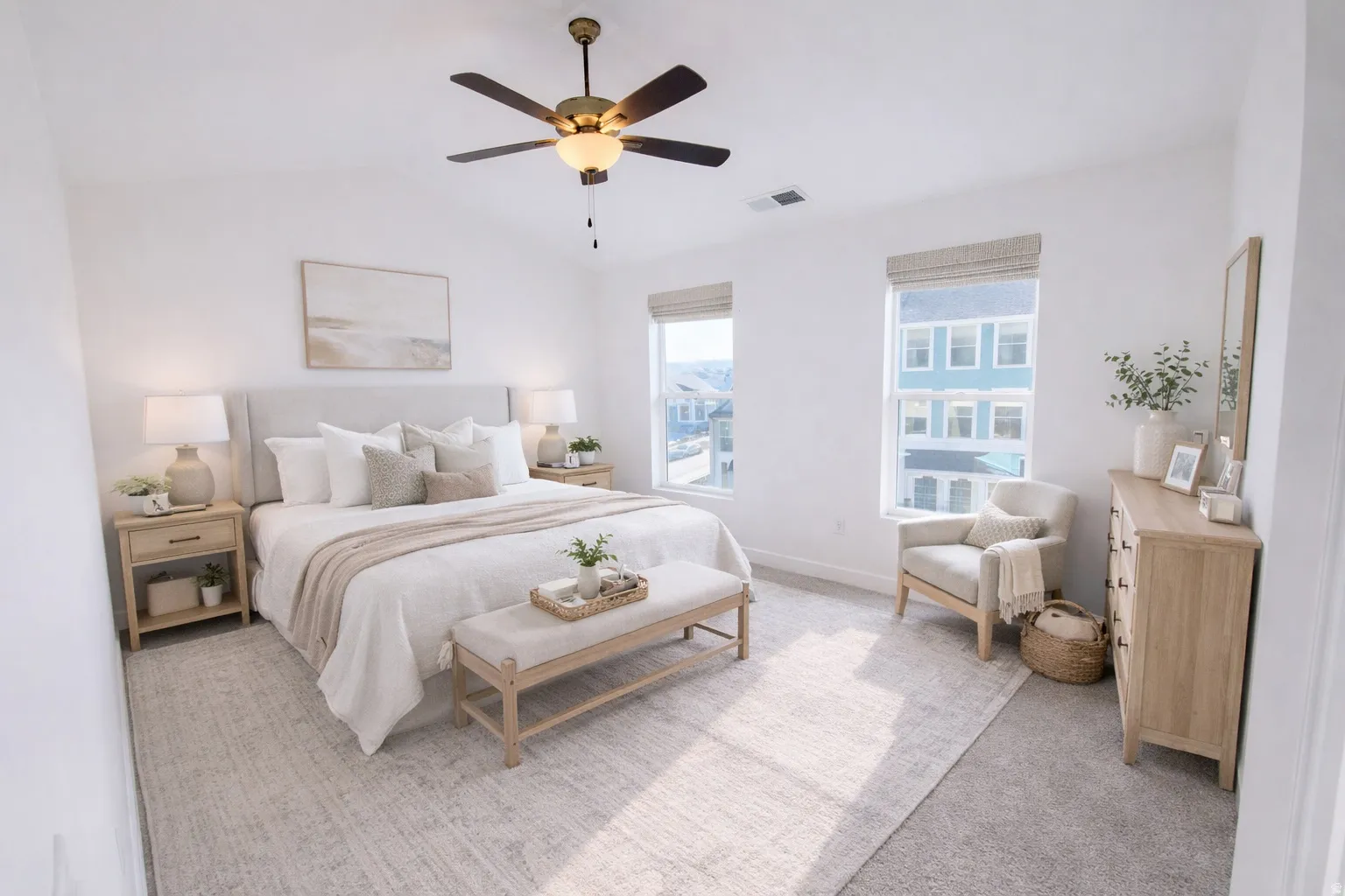 Spacious bedroom featuring light-toned carpeting and walls, a vaulted ceiling, and dual windows with natural light