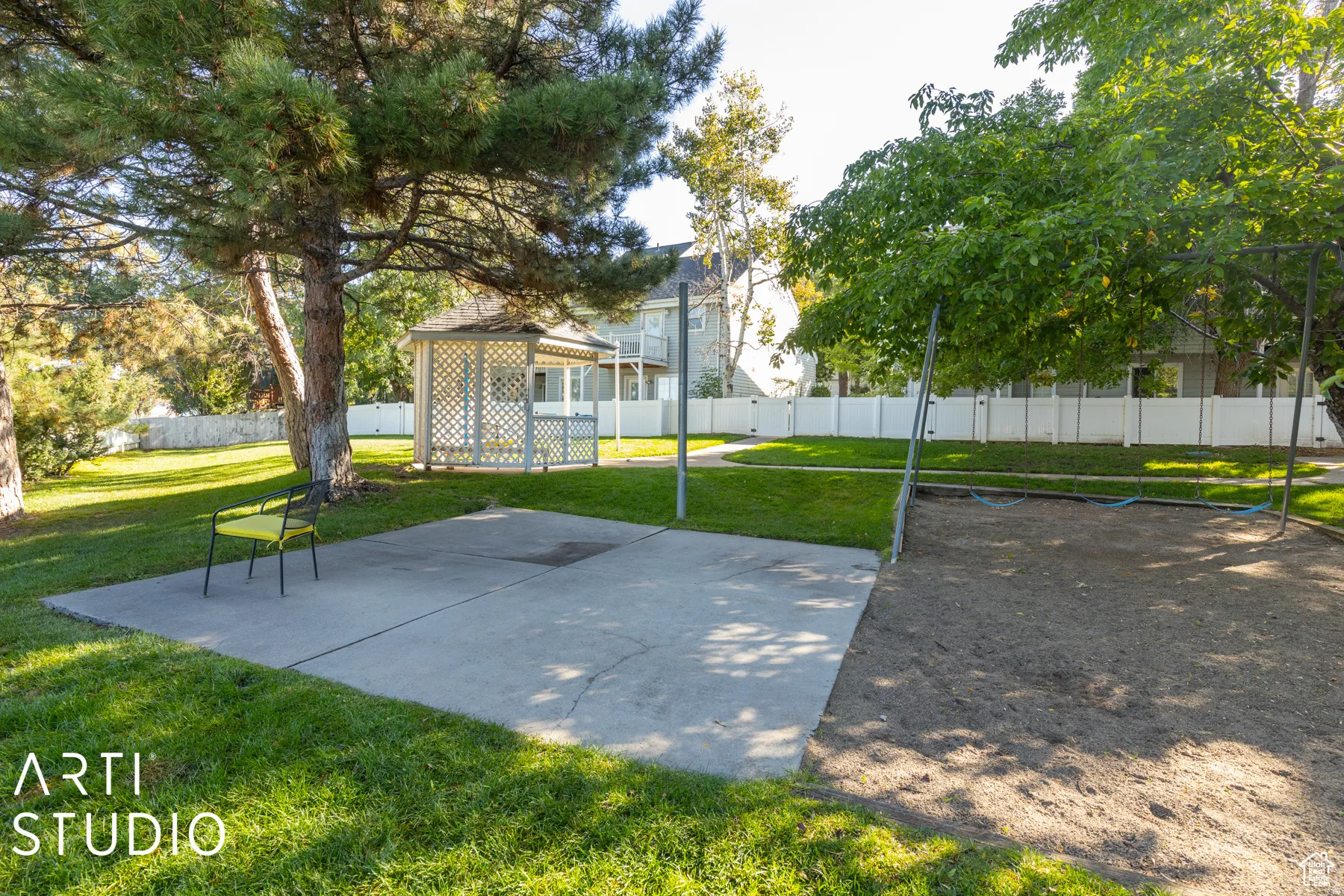 Expansive outdoor space featuring a concrete patio, a white lattice gazebo, and a large mature tree