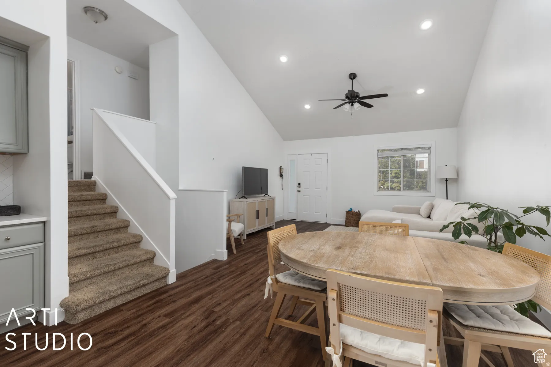 Open-concept living space featuring wood-finish flooring and a vaulted ceiling with recessed lighting