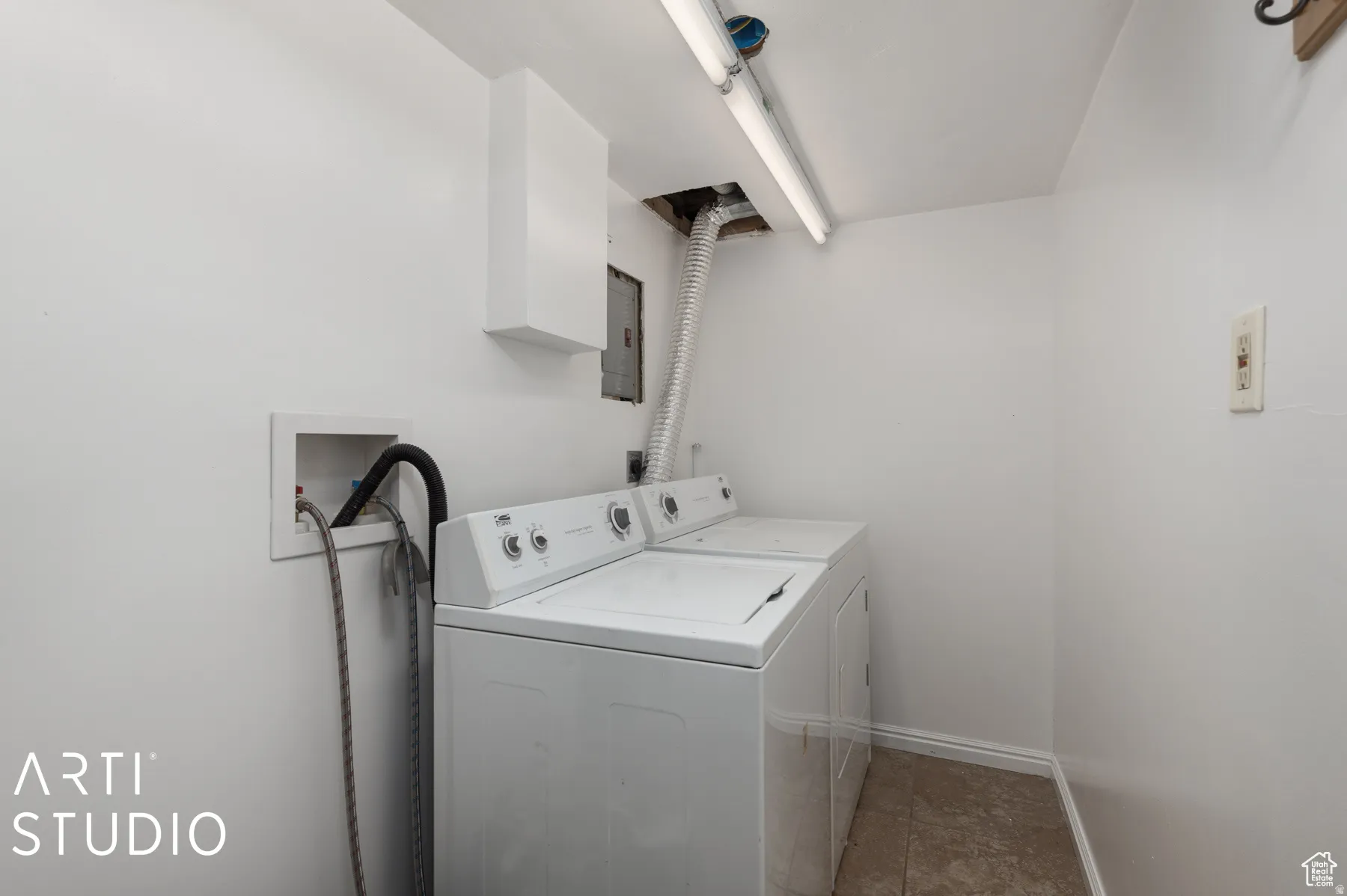 Dedicated laundry area featuring tile flooring, white walls, and overhead fluorescent lighting