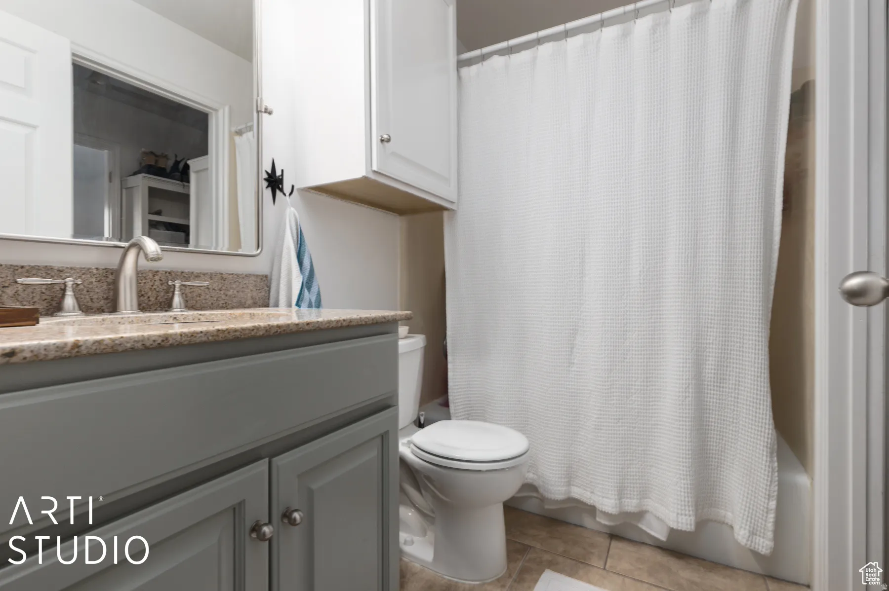 Bathroom vanity with a light gray base and a speckled countertop, featuring a single basin and brushed nickel faucet