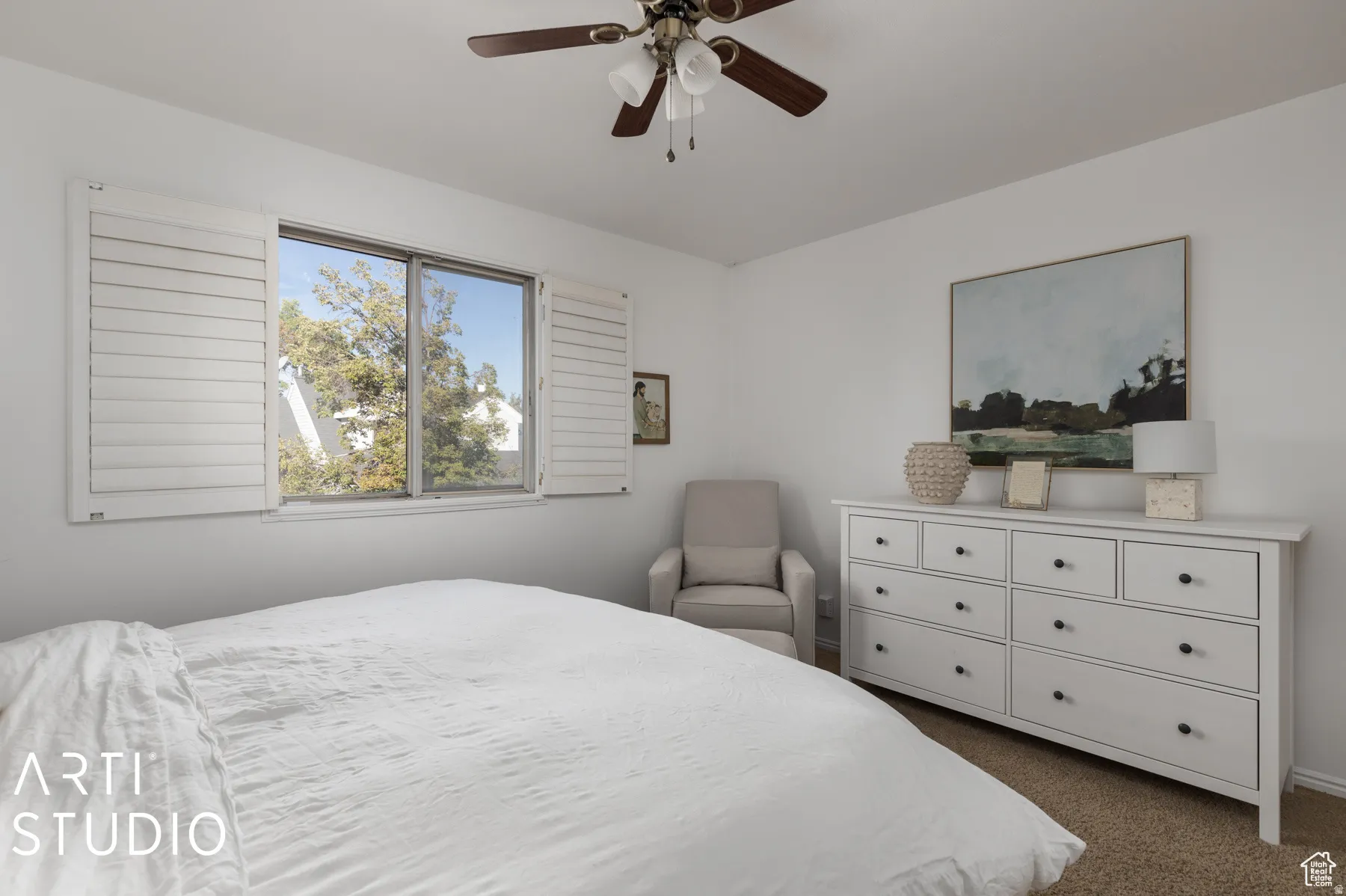 Bright room featuring a window with white louvered shutters, a ceiling fan with integrated lighting, and carpet flooring