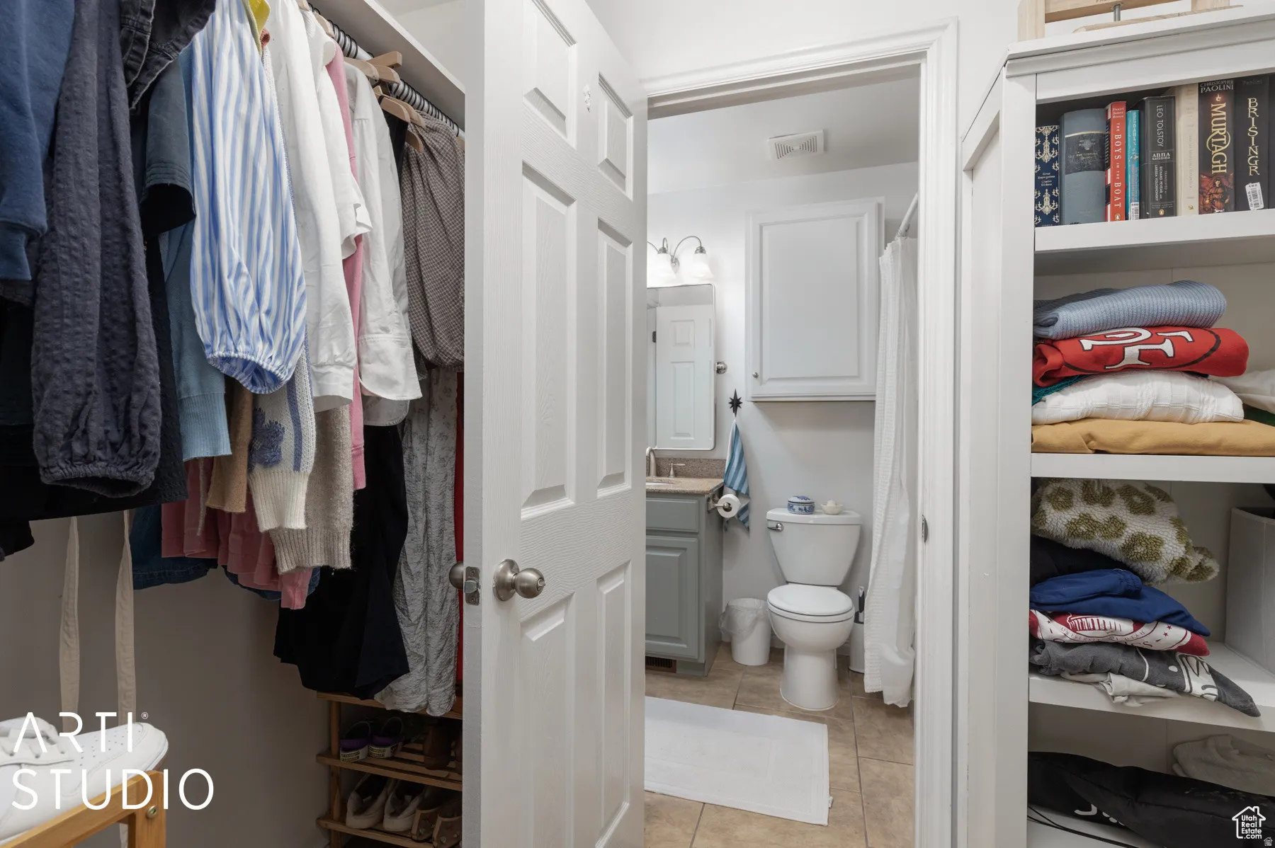 Walk-in closet with built-in shelving, hanging rods, and an adjacent bathroom entry