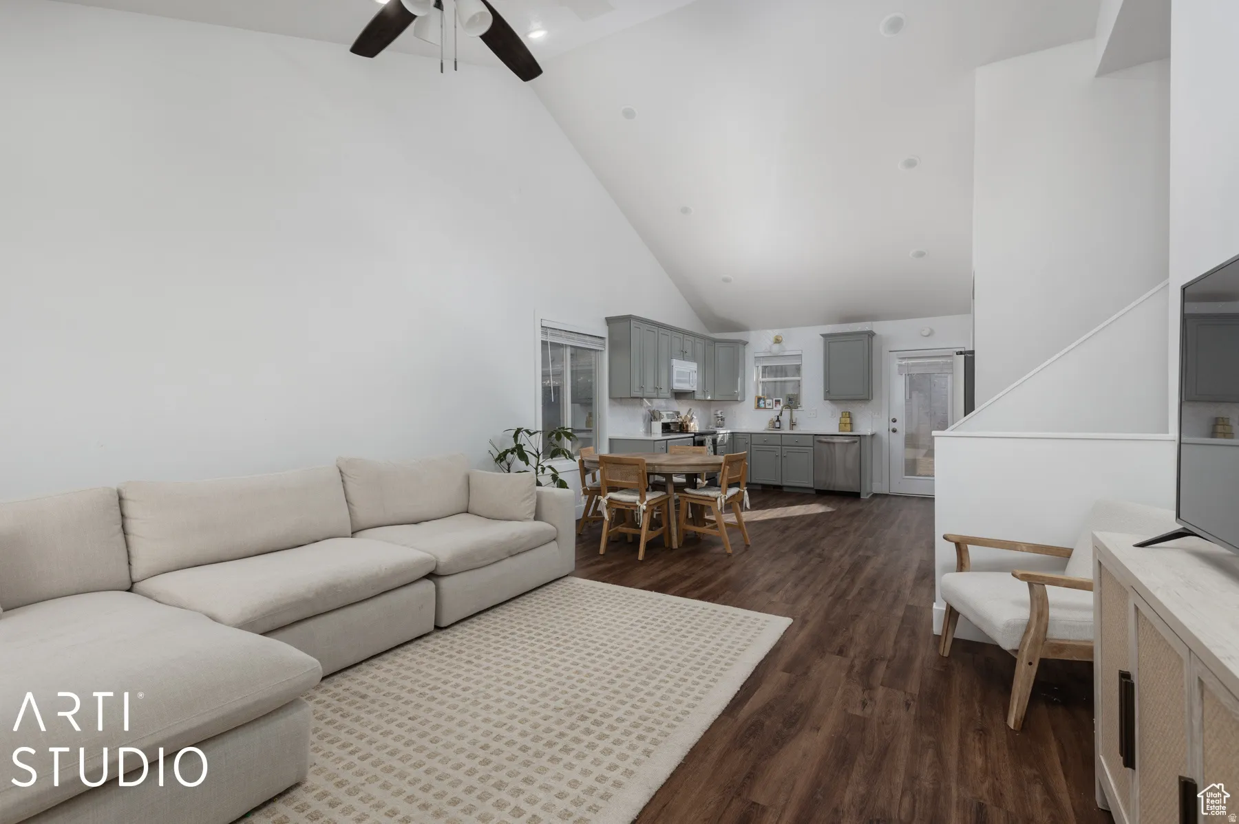 Spacious open-concept living area featuring vaulted ceilings, wood-finish flooring, recessed lighting, and a modern ceiling fan