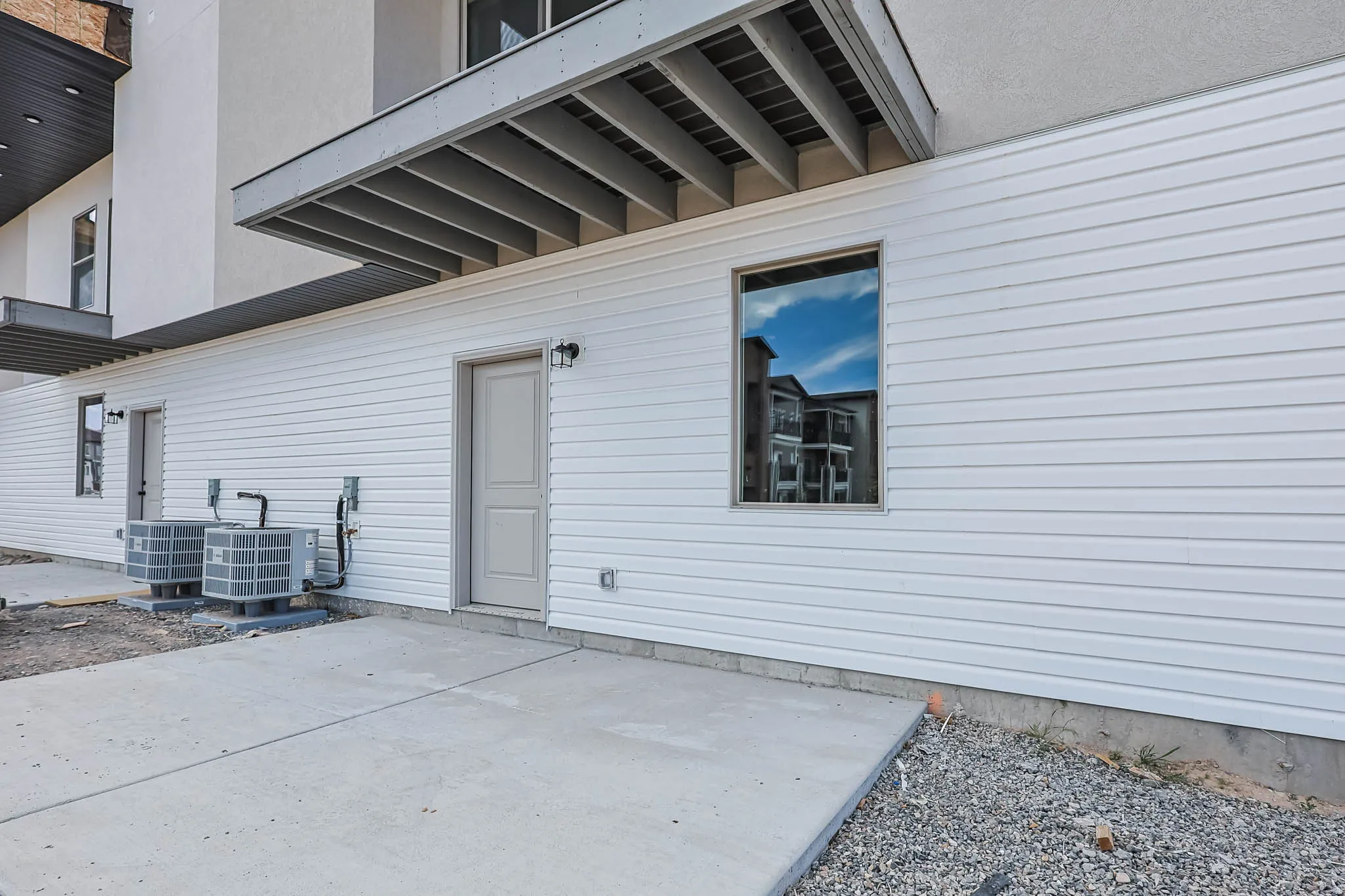 Exterior featuring white horizontal siding, a light-colored entry door, and a single-pane window