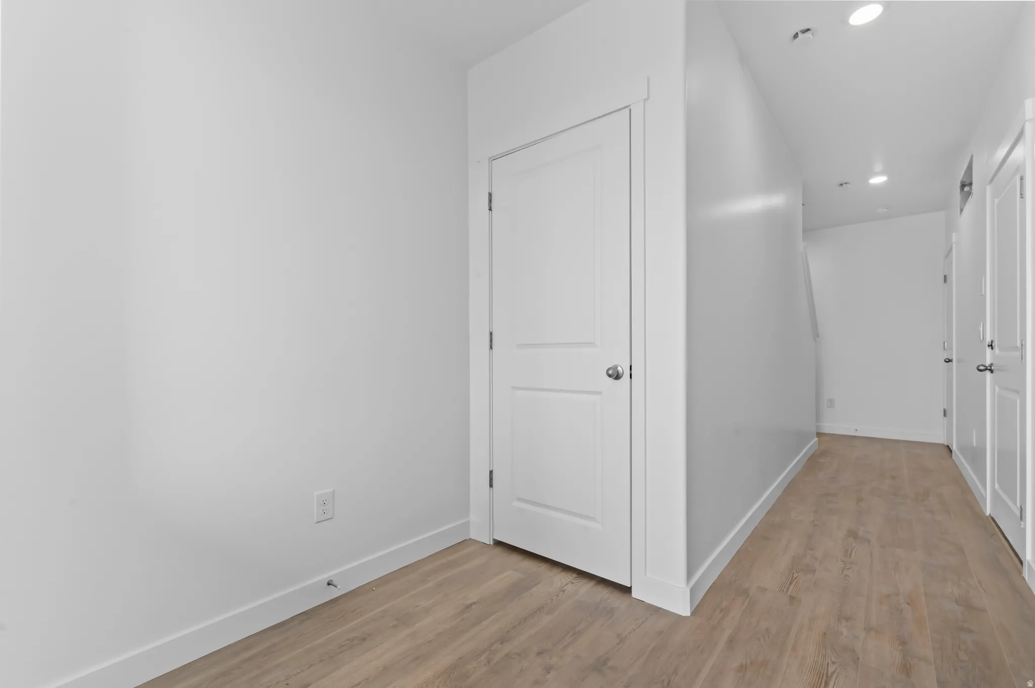Entryway featuring wood-finish flooring, white baseboards, a white interior door with a silver knob, and recessed lighting