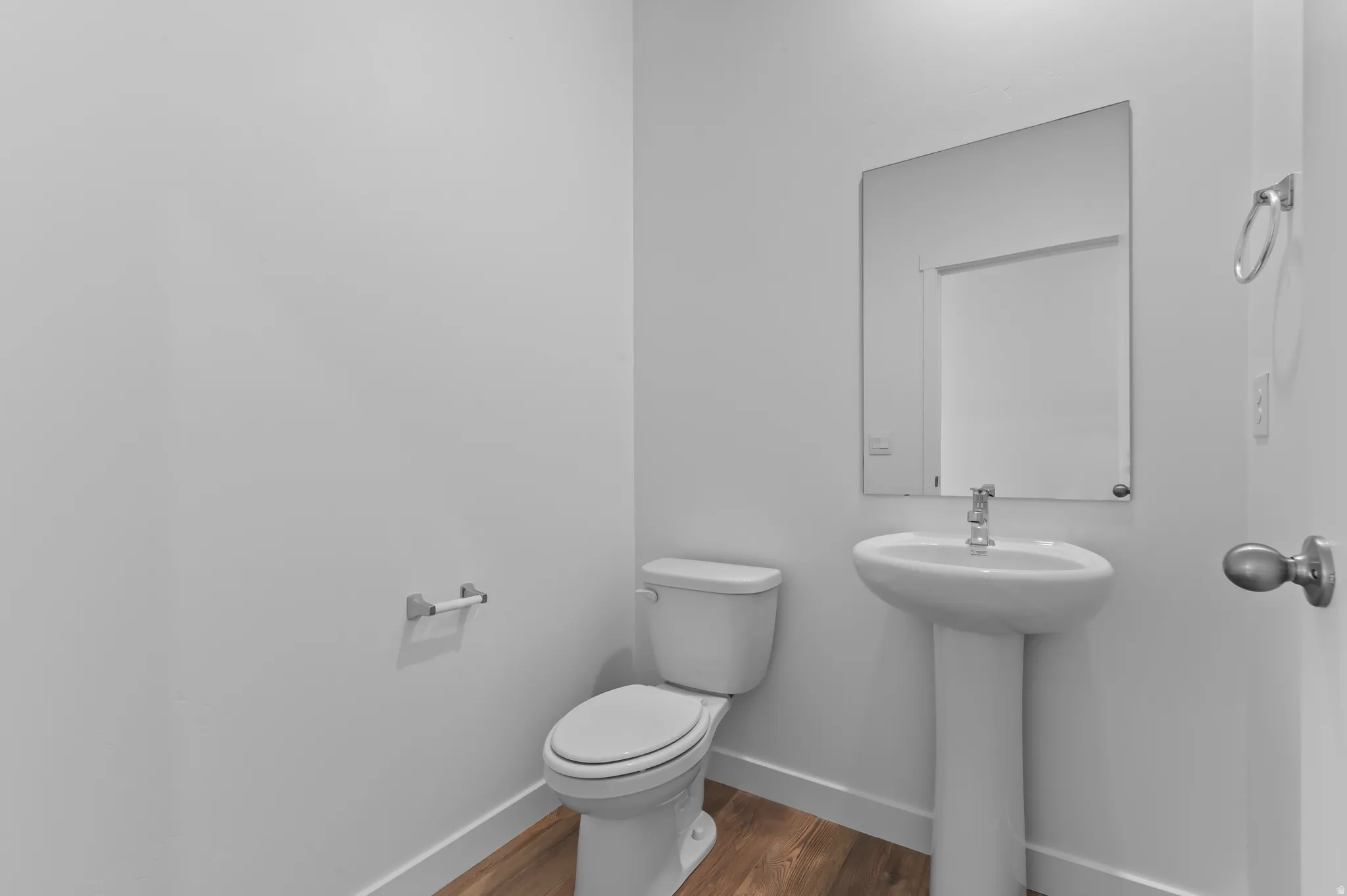 Pedestal sink with chrome faucet, complemented by a rectangular wall-mounted mirror