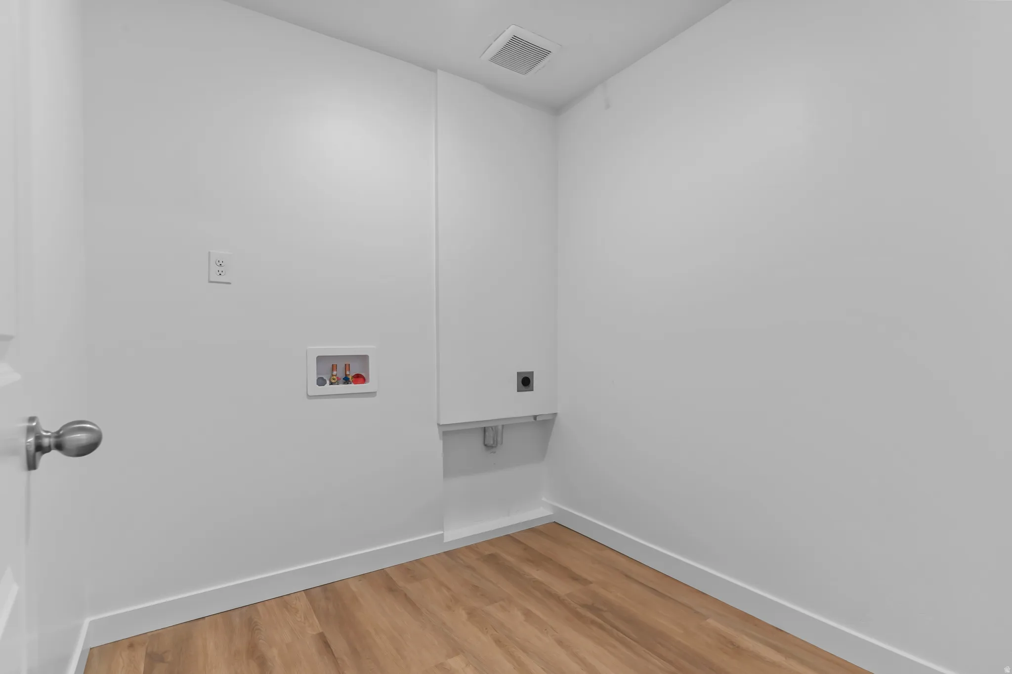 Utility area featuring wood-finish flooring, white walls, and a ceiling vent