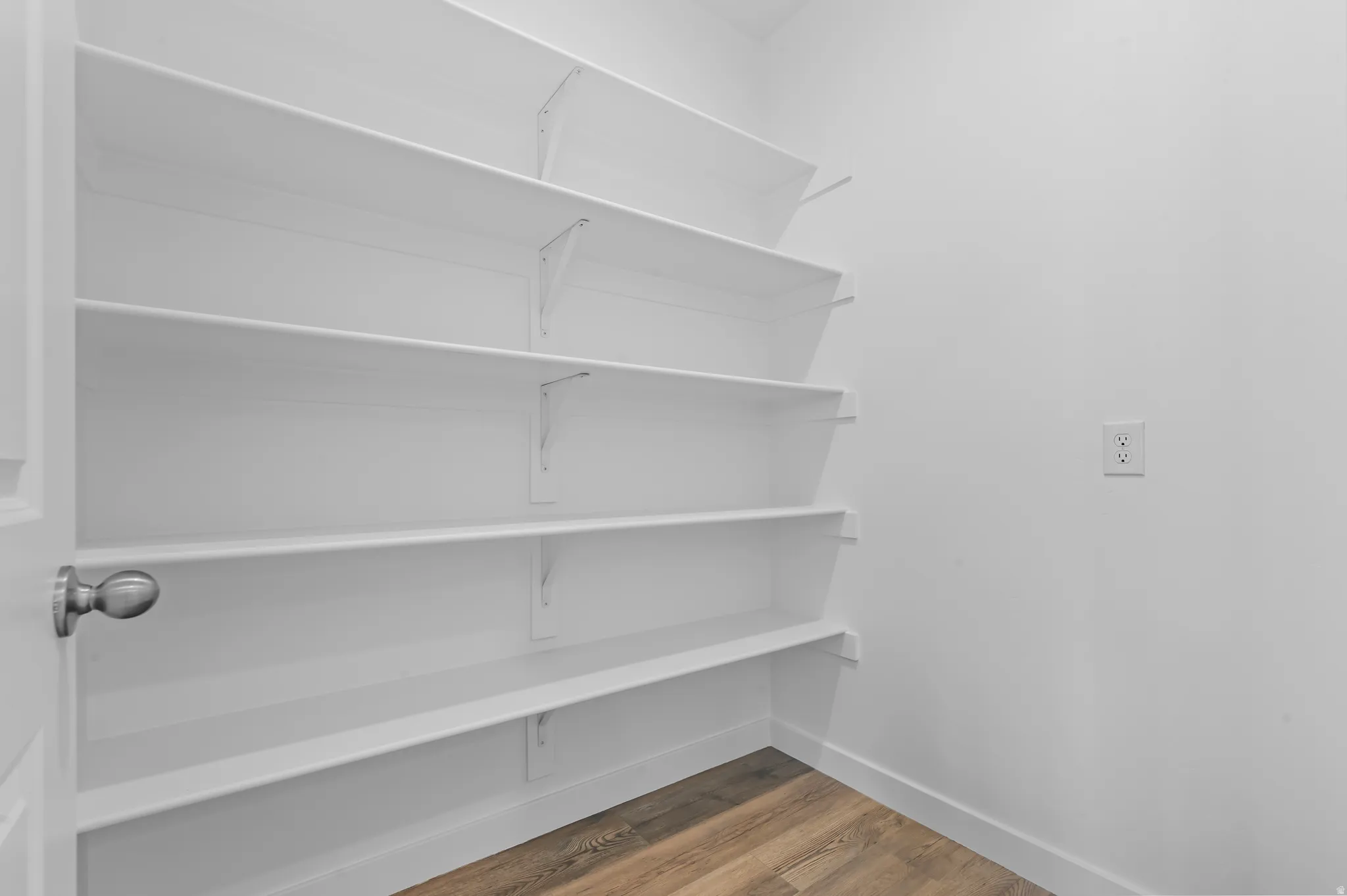 White painted shelving units with multiple tiers, wood-finish flooring, and white wall finishes