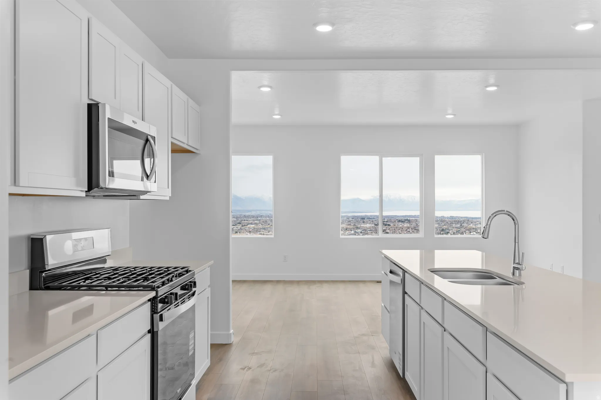 Modern kitchen featuring white cabinetry, light-toned countertops, and stainless steel appliances