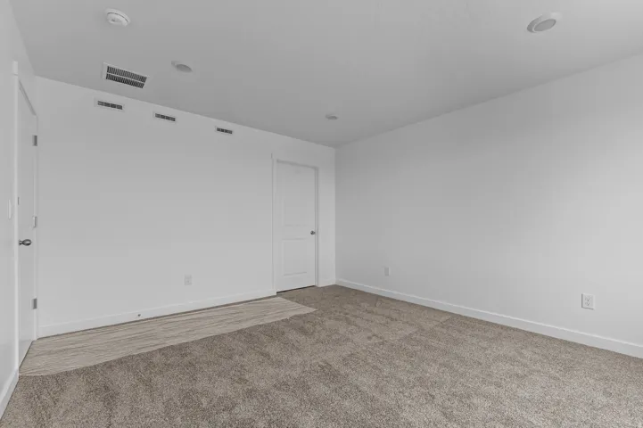 Spacious room featuring neutral carpeting and white walls