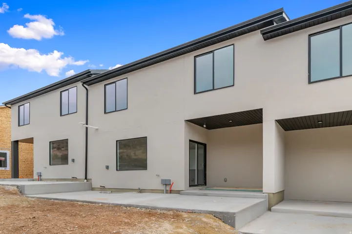 Modern exterior featuring light-colored stucco, dark-framed windows, and a dark soffit