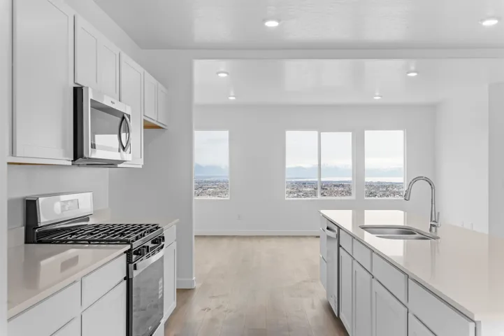 Modern kitchen featuring white cabinetry, light-toned countertops, and stainless steel appliances
