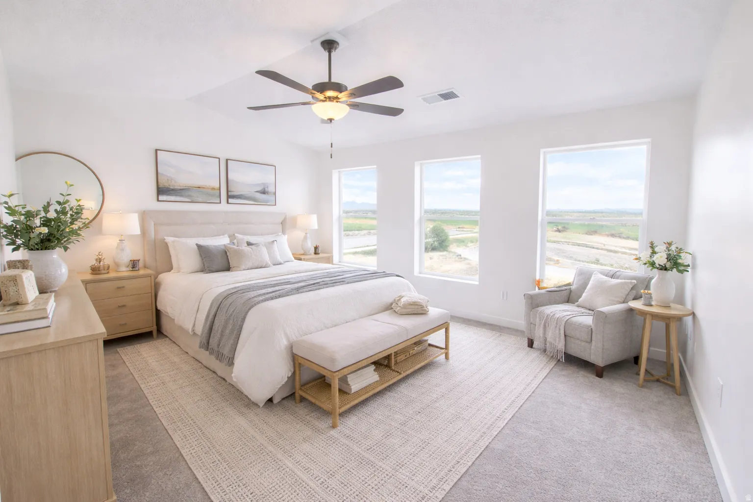 Bright interior space featuring a tray ceiling with a ceiling fan, three large windows, light gray carpeting, and white walls