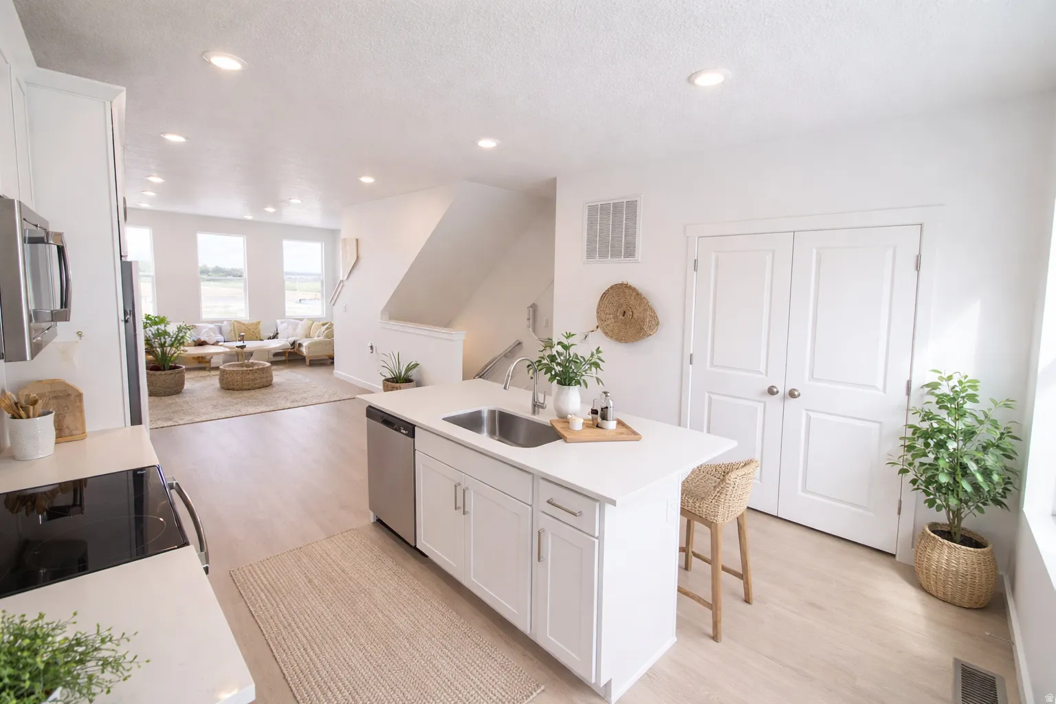 Modern kitchen featuring a central island with an undermount sink, stainless steel dishwasher, and white shaker cabinetry