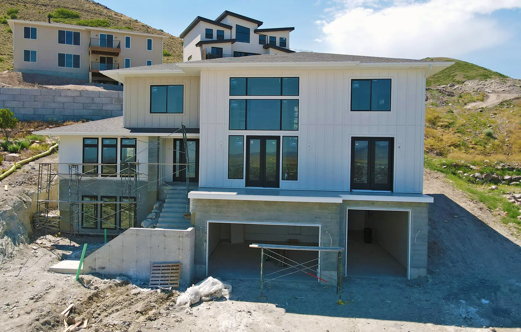 Modern multi-level residence featuring white vertical siding and black-framed windows